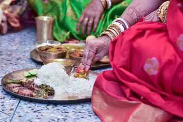 Obraz na płótnie Canvas Colourful traditional view of bengali wedding rituals while bride is mixing rice on a brass plate in india