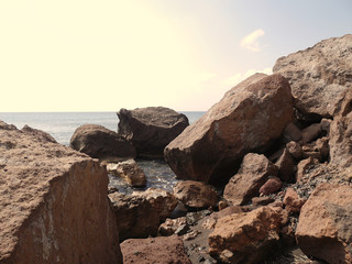 Landscape with cliffs and large stones on the coast near Akrotiri. Santorini, Greece.