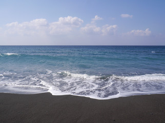 Fototapeta na wymiar Seascape on the island of Santorini, Greece. Sea waves with foam on a sunny day.