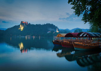 Three tourists boats standing in the  row on bled lake with castle on the background and island church. Draatic destination in Slovenia. 2019.Triglav national park.