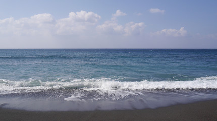 Fototapeta na wymiar Seascape on the island of Santorini, Greece. Sea waves with foam on a sunny day.