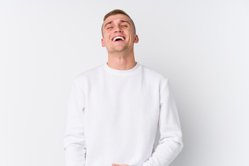 Young caucasian man on white background relaxed and happy laughing, neck stretched showing teeth.