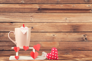 Fabric and paper hearts with cup and white sleigh on brown wooden table