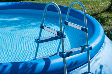 Blue round rubber inflatable family pool detail with ladder closeup