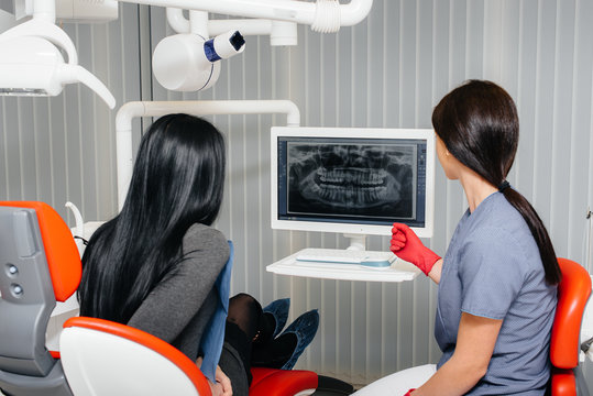 The dentist shows a picture of the patient's teeth and tells the necessary treatment. Dentistry, health.