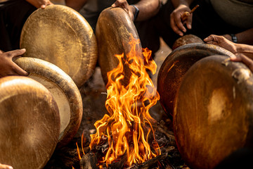 Tamil folk musical instrument "Parai"being tuned with heat from a makeshift bonfire by a team of performers just before staging their musical performance