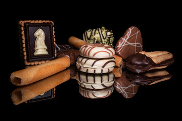 Sweet cookies and candies with reflection on shiny black background