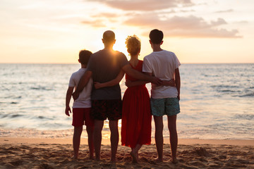 Happy family standing on the beach on the dawn time