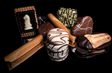 Sweet cookies and candies with reflection on shiny black background