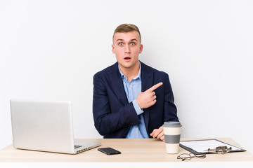 Young business man with a laptop pointing to the side