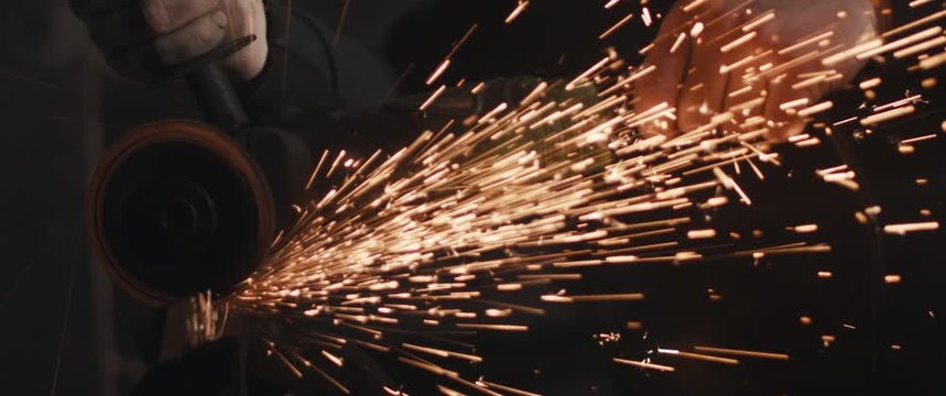 Blacksmith with angle grinder sparks unrecognizable dark close up cinemascope widescreen