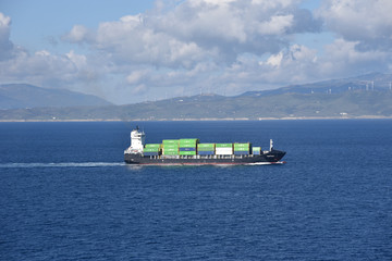 Small container ship sailing near sea coast close to Gibraltar. 