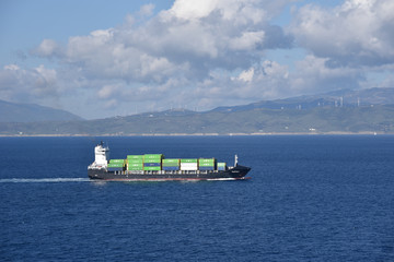 Small container ship sailing near sea coast close to Gibraltar. 