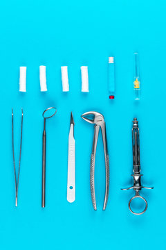 Set Of Dentist Tools And Equipment Isolated On Blue Background, Mirror, Metal Syringe With Anesthesia, Tweezers, Surgical Pliers And Cotton Wool Rolls, Dental Health And Teeth Care Concept, Top View