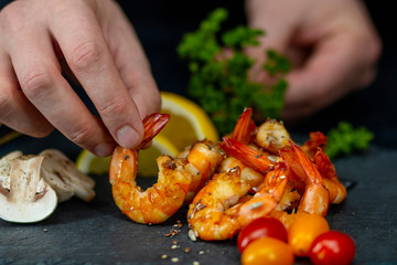 man decorates a dish of fried shrimp with vegetables on a stone tray