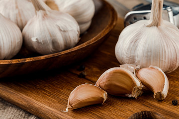 garlic cloves in wooden plate on burlap background