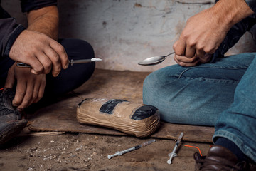 two shabby  men preparing drug injection in slums