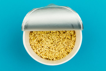 A plate of noodles on a blue background. Top view.