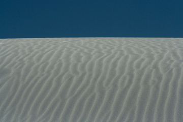 Background or Texture image with close-up of wave patterns on white gypsum dunes at White Sands National Park