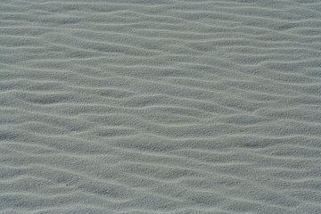 Background or Texture image with close-up of wave patterns on white gypsum dunes at White Sands National Park
