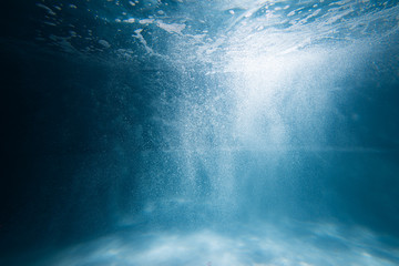 Air bubbles underwater rising to water surface, natural scene