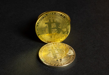 Shiny stack bitcoin coins on black textured background, close up view