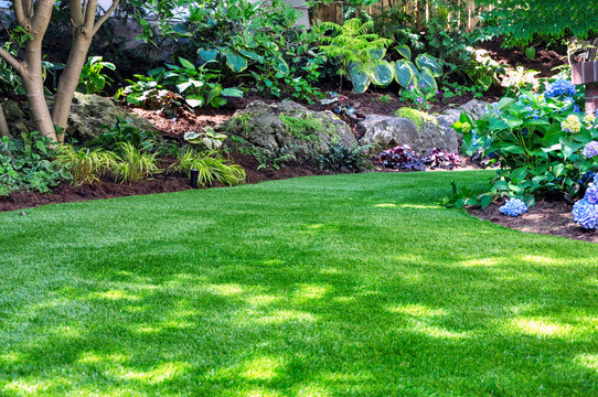 This beautiful backyard woodland garden features a maintenance free lawn made of natural looking artificial grass, a huge landscaping trend for small spaces.
