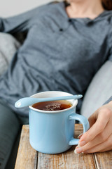 Woman relaxes in an armchair with a mug of tea.