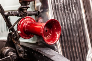 antique red car horn on front of old car