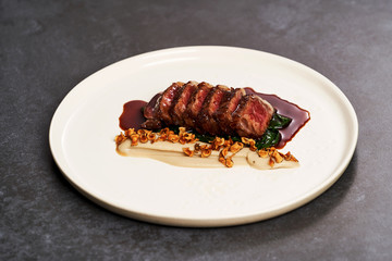 Sliced lamb meat and mashed potatoes on a white plate on gray table