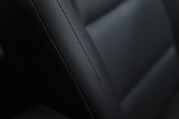 Part of stitched leather black leather car interior. Modern luxury car black perforated leather interior. Car leather interior details. Decorative seam