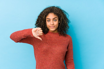 Young african american curly hair woman showing a dislike gesture, thumbs down. Disagreement...
