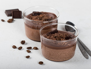 Italian dessert creamy chocolate and coffee jelly, Panna cotta with chocolate pieces in a glass Cup on a light background