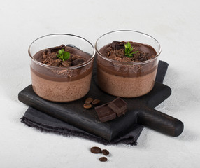 Italian dessert creamy chocolate and coffee jelly, Panna cotta with chocolate pieces in a glass Cup on a light background