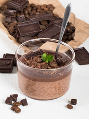 Italian dessert creamy chocolate and coffee jelly, Panna cotta with chocolate pieces in a glass Cup on a light background