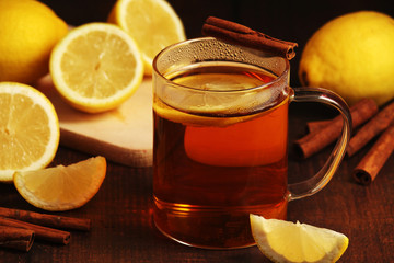A mug with hot tea with lemons and cinnamon sticks	