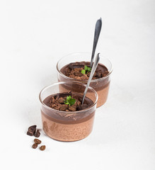 Italian dessert creamy chocolate and coffee jelly, Panna cotta with chocolate pieces in a glass Cup on a light background