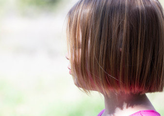 profile of young girl, about 4 years old, with short hair and blurred bright outdoor background