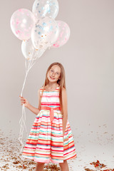 Inclusive Beauty. Girl with freckles in dress standing isolated on grey holding balloons posing smiling joyful