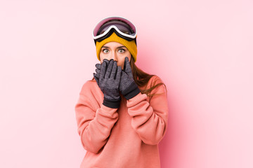 Young caucasian woman wearing a ski clothes isolated shocked covering mouth with hands.