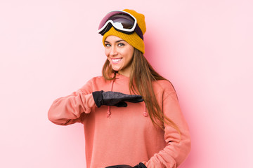 Young caucasian woman wearing a ski clothes isolated holding something with both hands, product presentation.