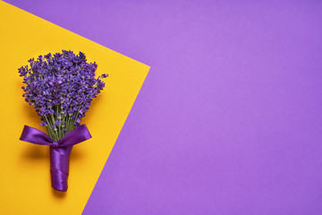 Bunch of lavender flowers on yellow-purple background. Top view, copy space.