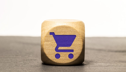 Icone shopping / consommation gravé sur un cube en bois, isolé sur une ardoise
