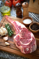 fresh raw tomahawk steak on wooden cutting board