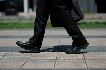 朝の駅前で革靴とスーツで歩く男性の足元