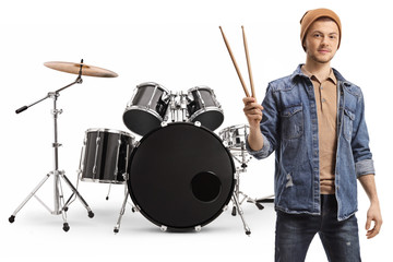 Young guy holding drumsticks and posing with a set of drums