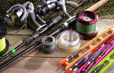 Fishing rods and spinnings in the composition with accessories for fishing on the old background on the table