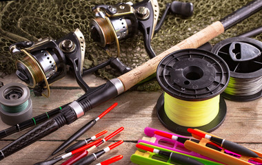 Fishing rods and spinnings in the composition with accessories for fishing on the old background on the table