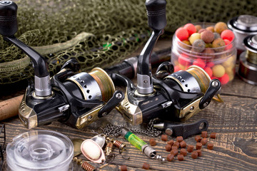 Fishing rods and spinnings in the composition with accessories for fishing on the old background on the table