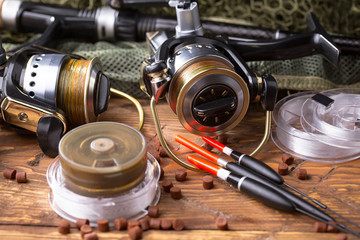 Fishing rods and spinnings in the composition with accessories for fishing on the old background on the table